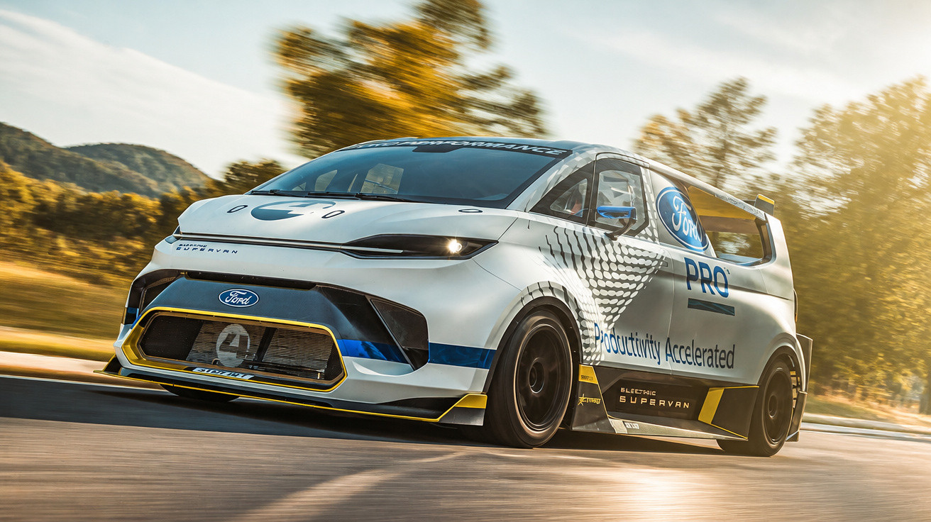 Ford Pro Electric SuperVan branca em alta velocidade em estrada com árvores ao fundo.