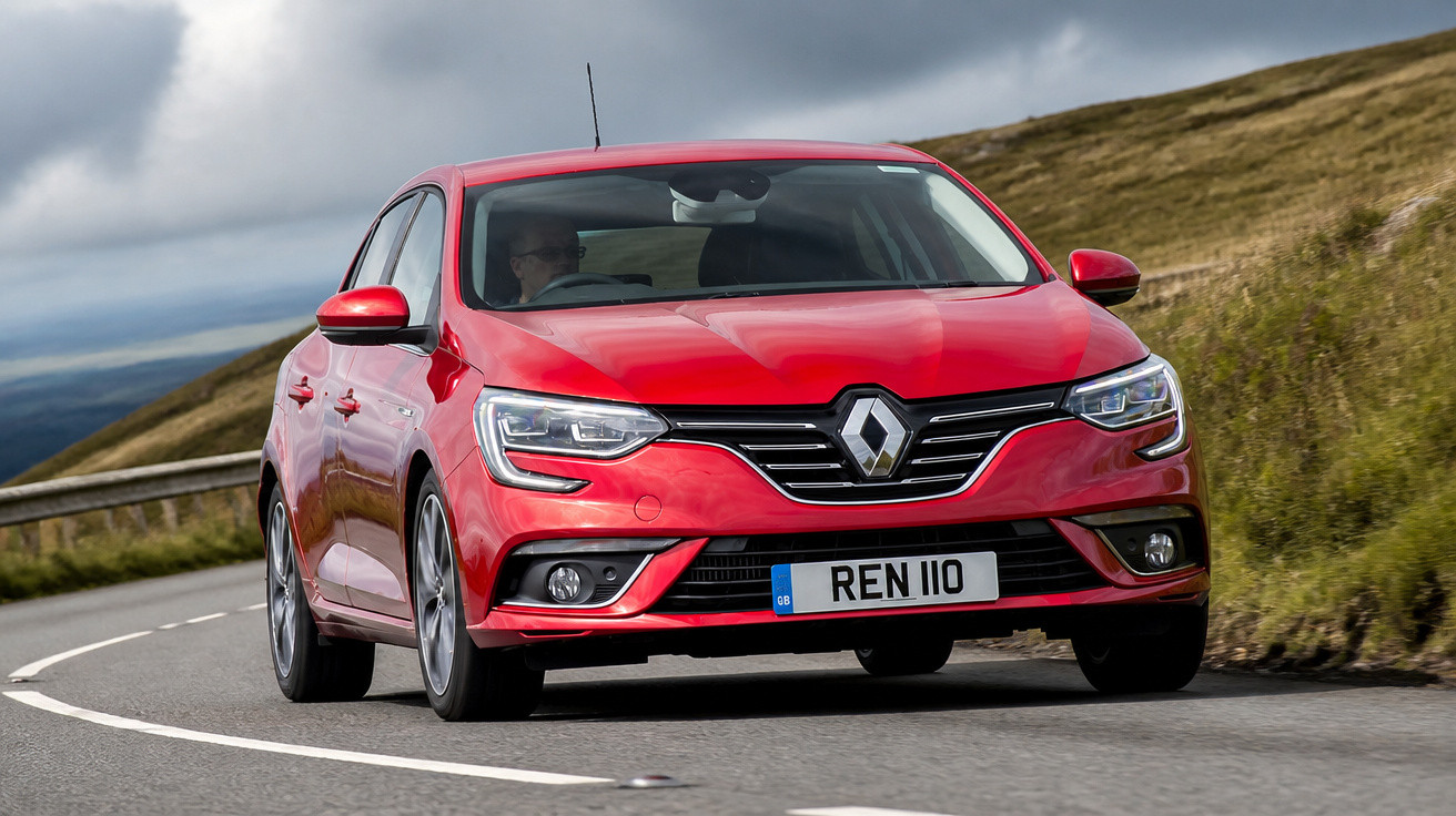 Carro vermelho Renault modelo hatchback dirigindo em estrada curvada com paisagem de colinas.