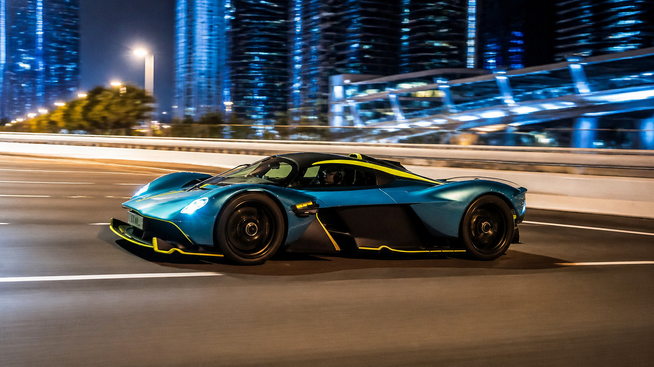 Carro esportivo azul com detalhes amarelos em alta velocidade em rua urbana à noite.