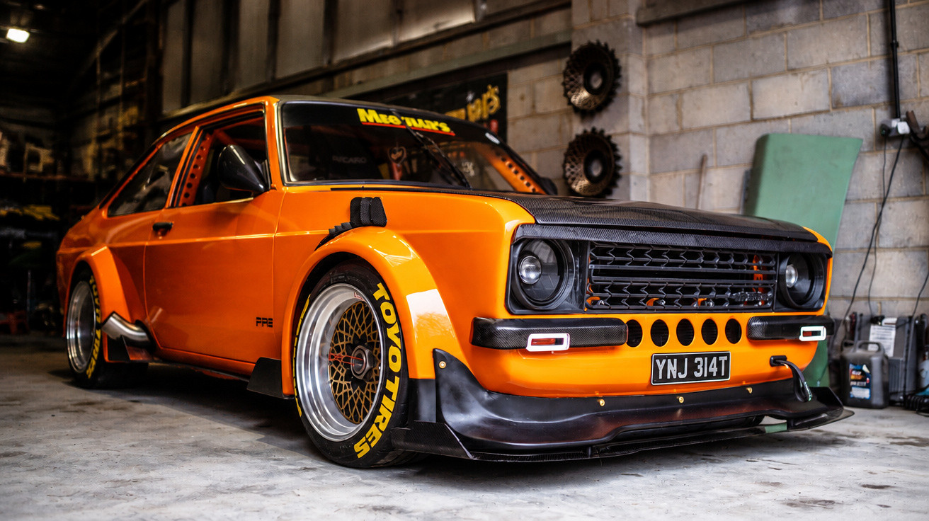 Carro esportivo clássico laranja personalizado estacionado em garagem com parede de blocos cinza.
