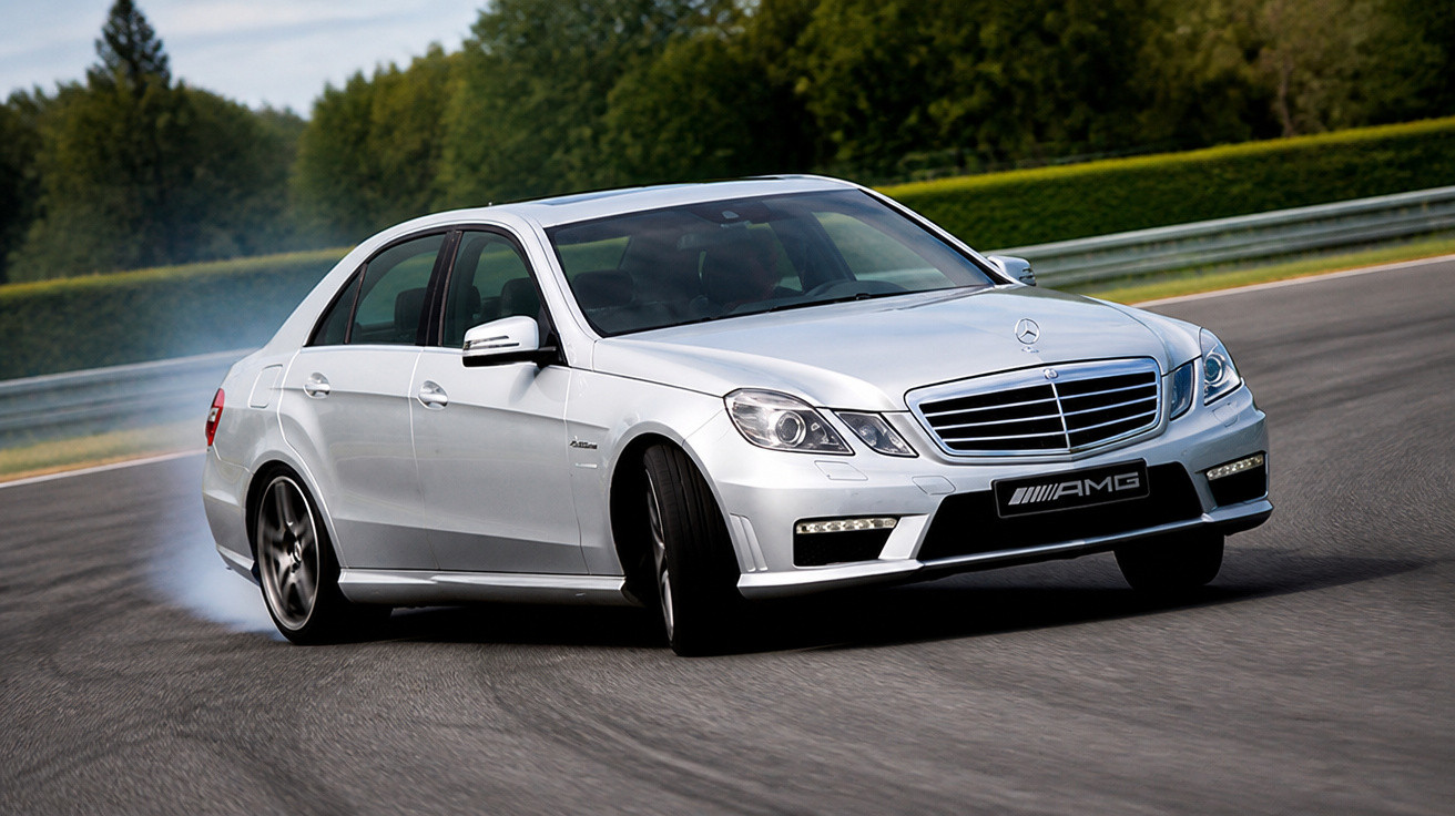 Carro prata Mercedes-Benz AMG fazendo curva em pista de corrida, com fumaça saindo do pneu traseiro.