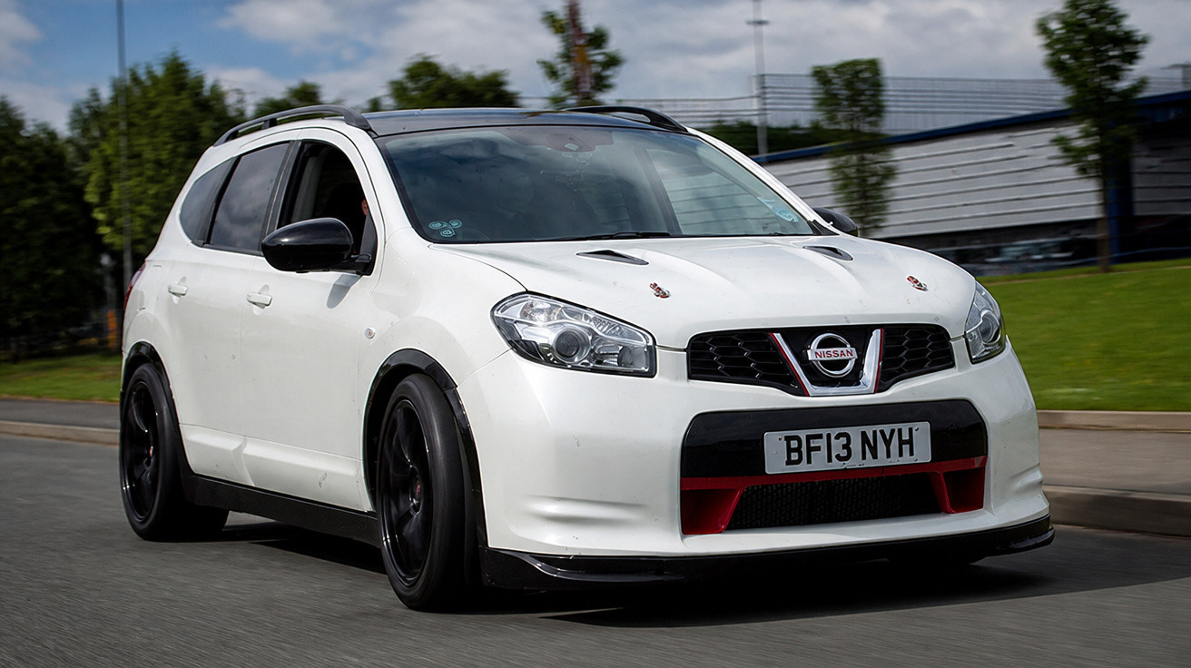 Carro esportivo branco Nissan em movimento em estrada urbana com céu nublado ao fundo.
