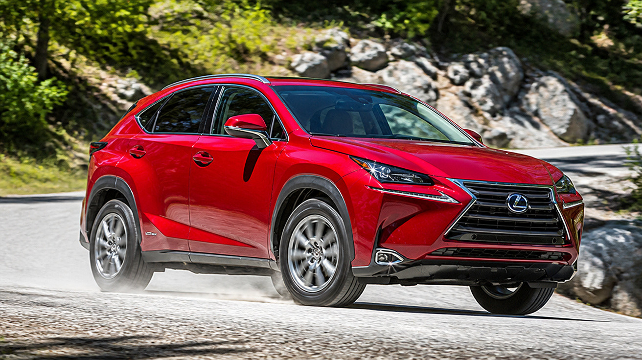 SUV vermelho Lexus NX 300h em movimento em estrada de estrada sinuosa cercada por pedras e árvores.