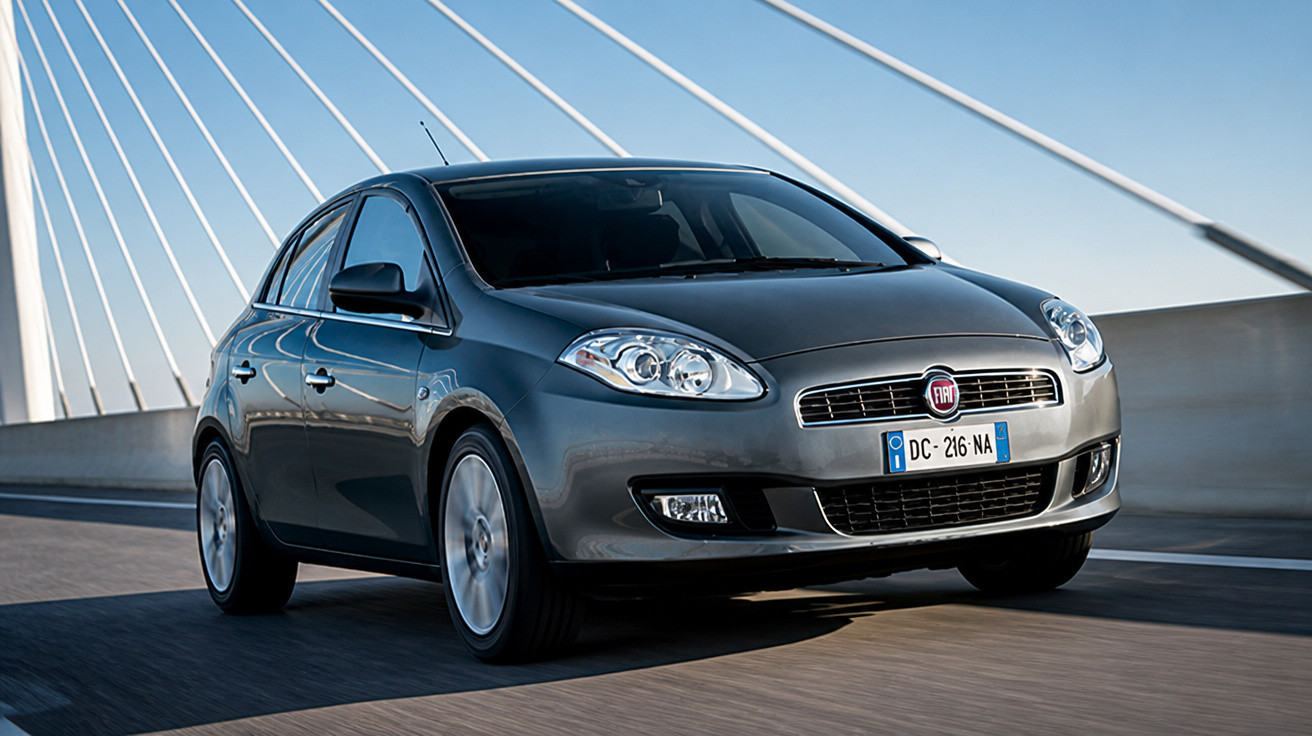 Carro cinza Fiat Punto em movimento sobre ponte com estrutura em cabos brancos.