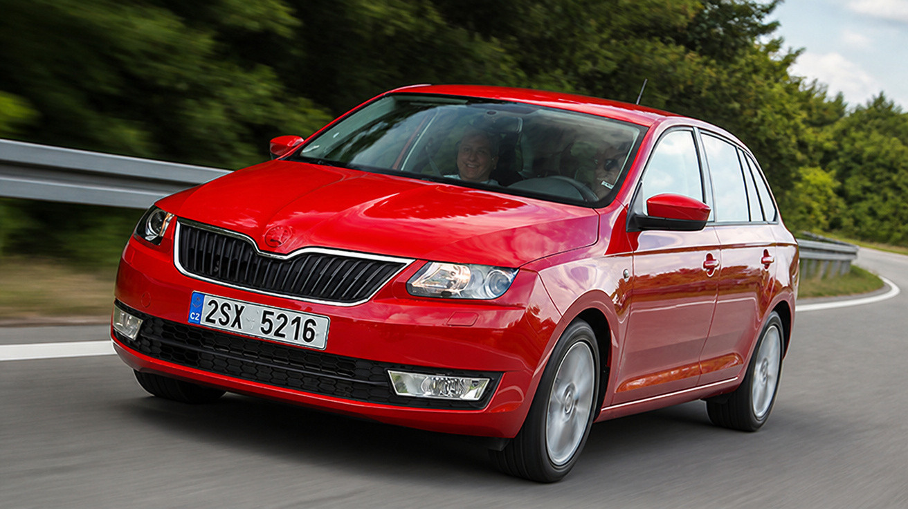 Carro vermelho modelo Skoda dirigindo em estrada curva com vegetação ao fundo.