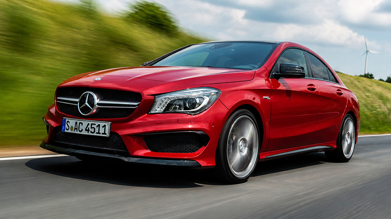 Carro Mercedes-Benz vermelho em alta velocidade em estrada cercada por grama e moinho de vento.