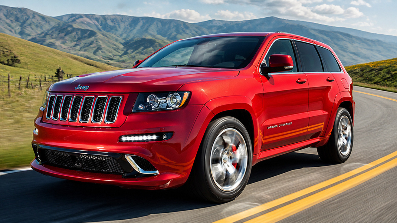SUV Jeep Grand Cherokee vermelho trafegando em estrada sinuosa com montanhas ao fundo.