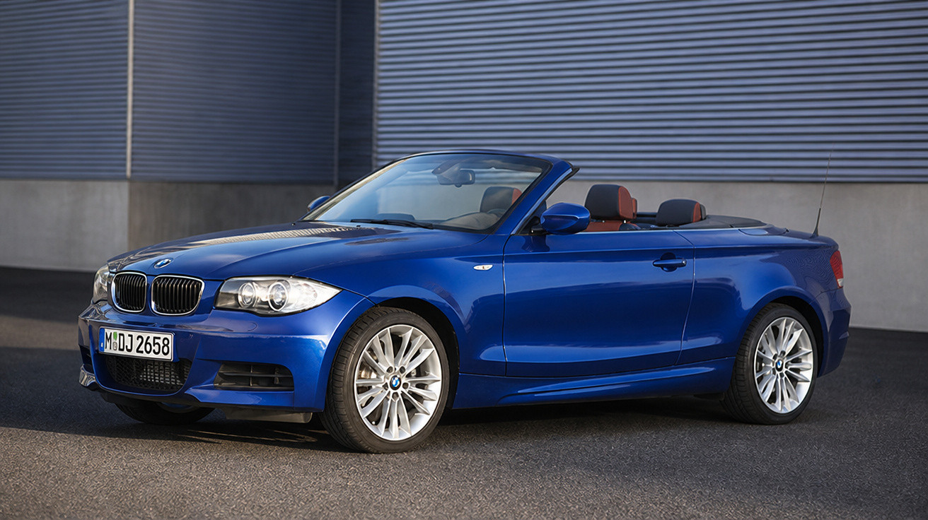 Carro conversível esportivo BMW azul estacionado em área urbana, vista lateral com interior marrom.