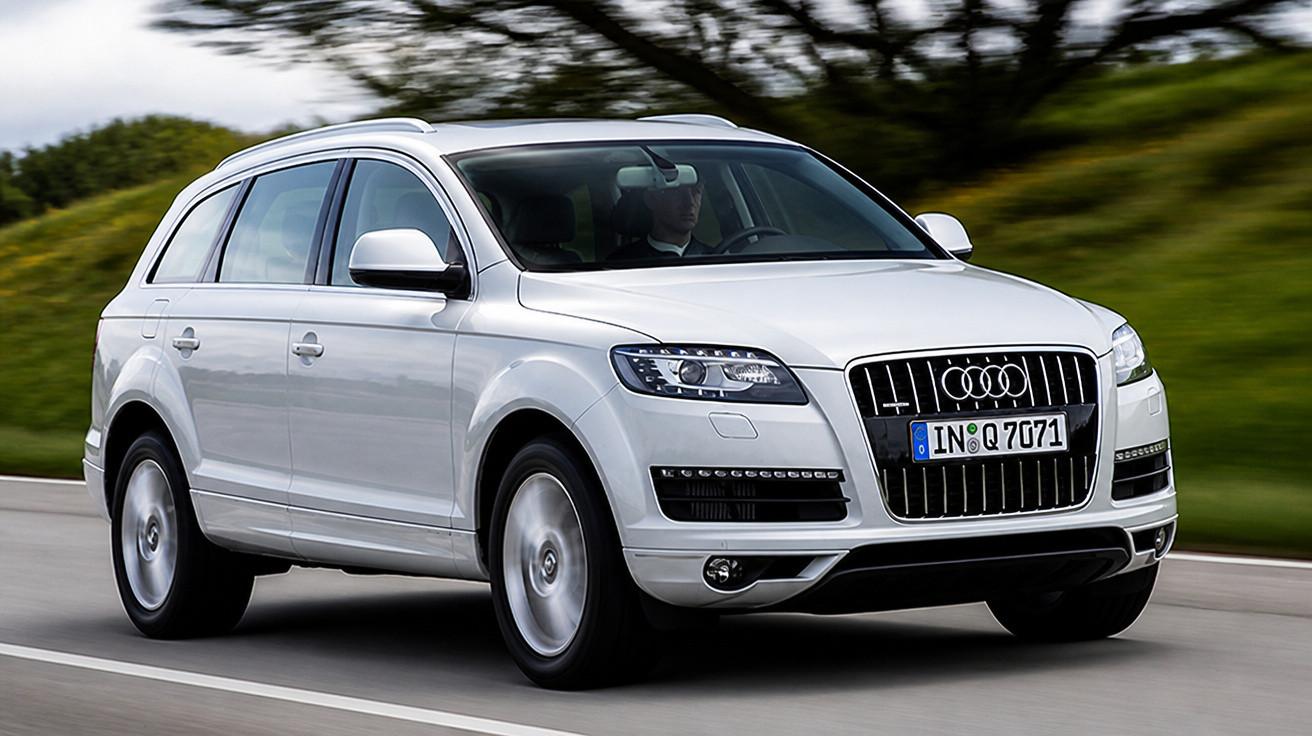 SUV Audi Q7 branco em movimento em estrada com fundo verde desfocado.